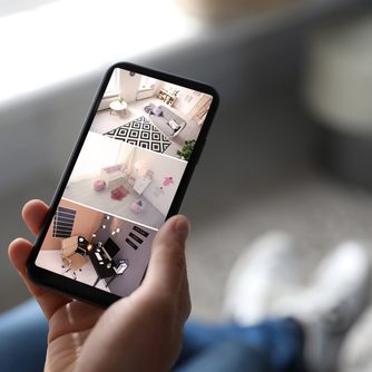 Image of homeowner on phone monitoring cameras covered by nc residential security system from Protection Systems, inc.